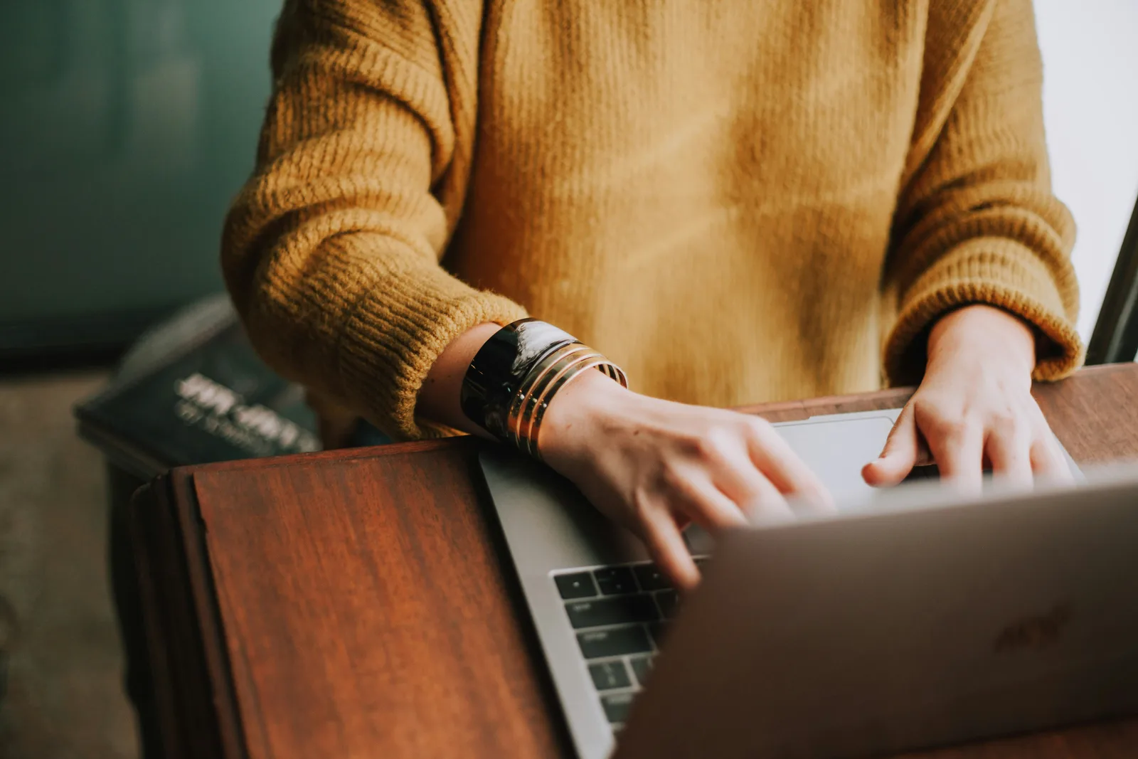 Hands typing on a laptop at a wooden table